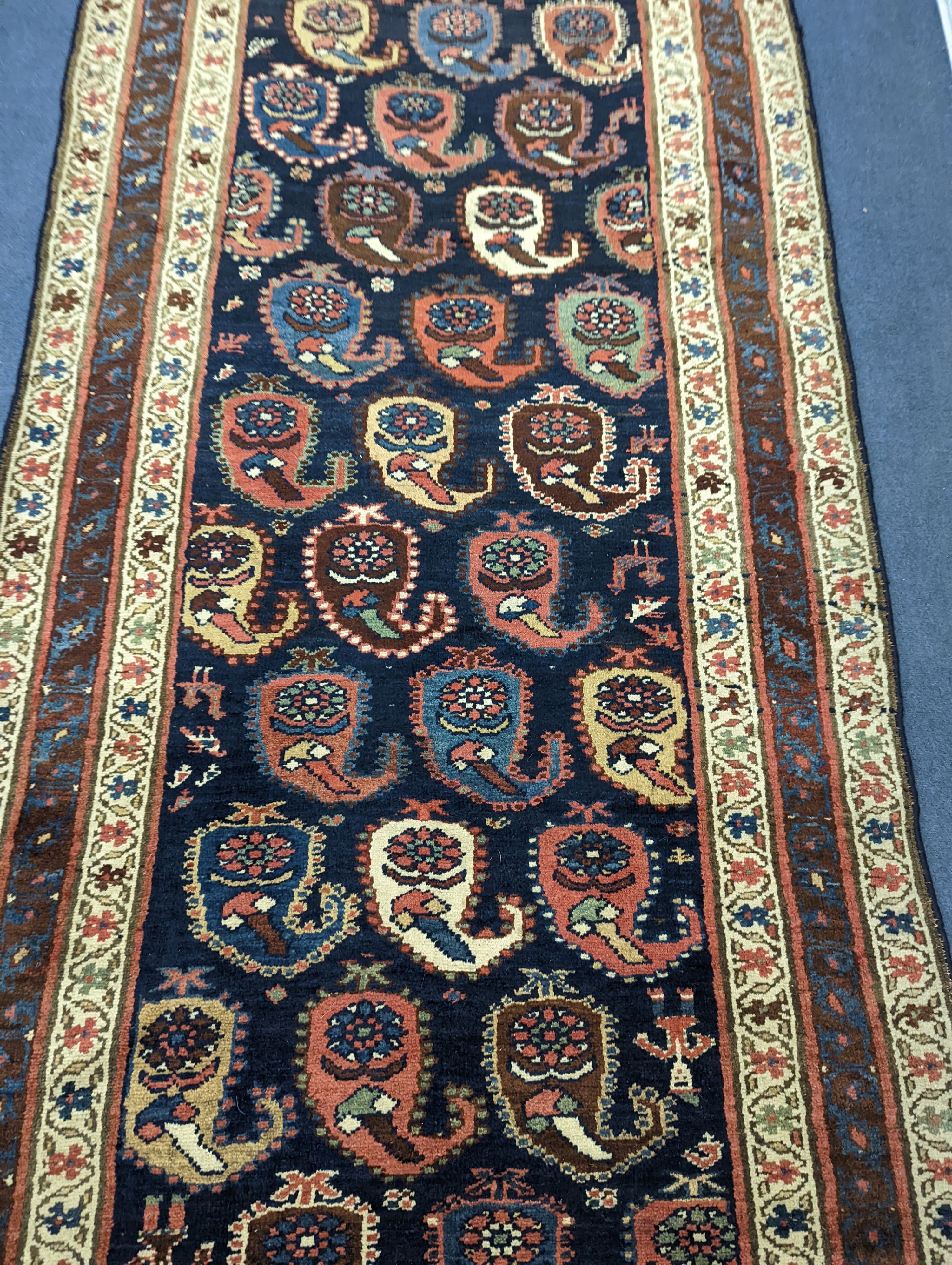 A Caucasian Karabagh blue ground runner, woven with rows of stylised boteh, figures and birds, 477 x 117cm